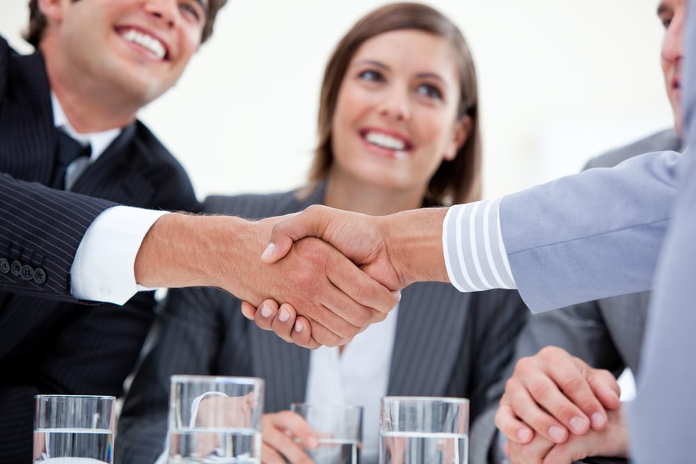 Smiling businessman and his colleague closing a deal with a partner in a meeting Smiling businessman and his colleague closing a deal with a partner in a meeting